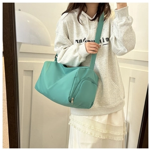 Detail of mint green oxford shoulder bag featuring a side zipper pocket and wide strap