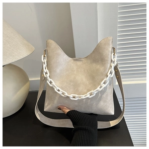 Close-up of white crossbody bag with cat-ear shape, chunky chain and pleated texture