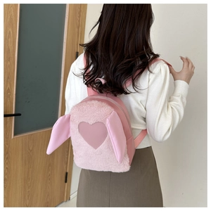 Close-up of pink plush backpack with long rabbit ears and heart patch on model