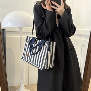 Chic striped canvas tote bag with blue and white patterns and adjustable shoulder strap