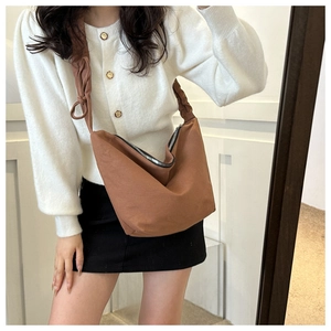 Detail of coffee brown canvas hobo bag featuring a pleated shoulder strap and metal zipper