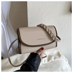 Detail of beige lychee grain leather bag with brown contrast edges and woven handle