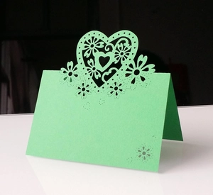 Dettaglio di cuori e fiori tagliati al laser su un segnaposto verde per matrimoni
