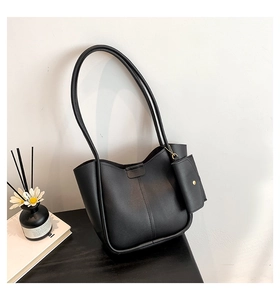 Detail of minimalist black tote bag with litchi grain texture and small coin pouch