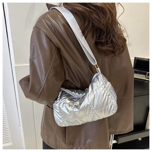 Modern quilted silver puffer shoulder bag shown on model with adjustable grey strap