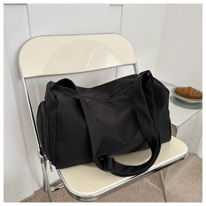Detail of black waterproof oxford tote bag on chair showing side zipper and adjustable strap