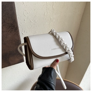 Detail of the litchi pattern faux leather texture and woven shoulder strap on the square bag
