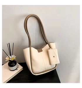 Close-up of cream shoulder bag with brown edges and detachable small coin purse pouch