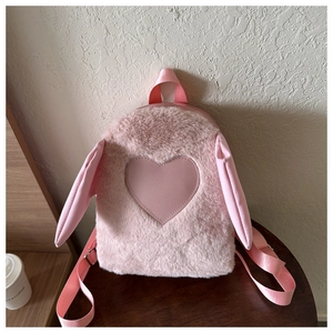 Detail of light pink plush backpack featuring leather heart patch and cute rabbit ears