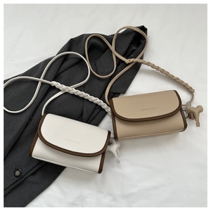 Detail of crossbody bag with litchi texture, contrast trim and elephant charm