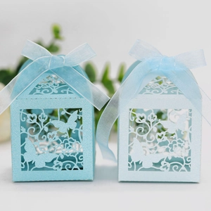 Detail showing laser-cut butterfly house candy boxes with blue glitter finish and ribbons
