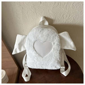 Detail view of white plush heart backpack with cute wing design on a wooden stool
