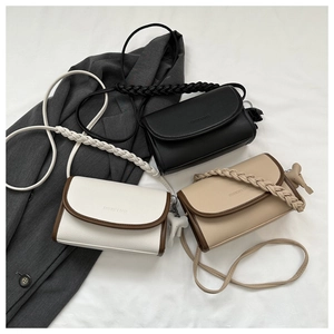 Close-up of contrast square handbags with braided handles and decorative charms on a suit