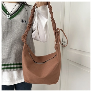 Detail of hobo bag in brown canvas with gathered strap and bow tie detail