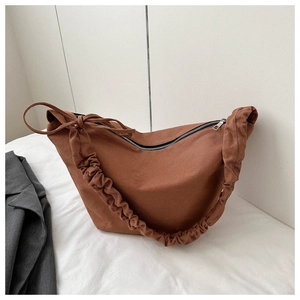 Detail of tan canvas hobo bag with unique pleated shoulder strap and silver metal zipper