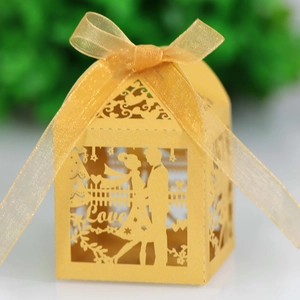 Detail of laser-cut gold wedding favor box with love motif and golden ribbon bow