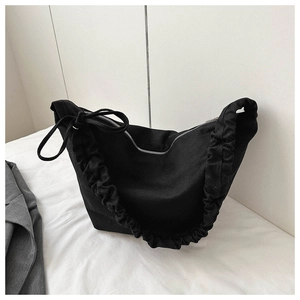 Detail view of black canvas crossbody bag featuring pleated strap and zipper closure