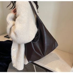 Deep brown matte faux leather tote bag shown styled with a beige knit cardigan for commuting