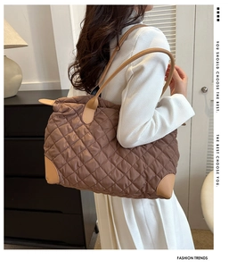 Détail d'un grand sac cabas matelassé marron foncé avec coins renforcés porté à l'épaule