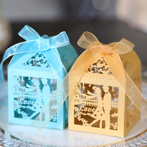Macro view of laser-cut wedding candy boxes in blue and gold with silk ribbons