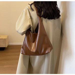 Brown large PU leather tote bag shown on model with a beige coat for daily office use