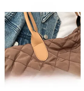 Détail d'un sac cabas marron matelassé avec surpiqûres en losange et anses en cuir