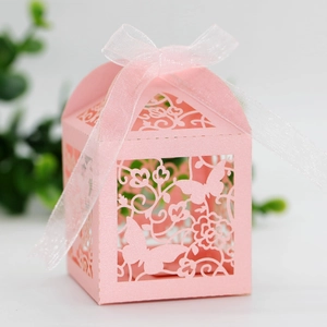 Detail of pink laser-cut wedding favor box with butterfly motifs and white ribbon bow