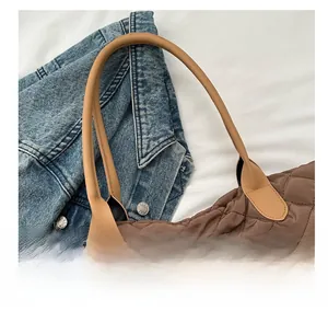 Détail de la poignée en cuir beige et du tissu marron matelassé de ce sac fourre-tout