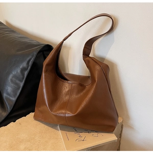 Macro detail of caramel brown leather tote bag with soft texture and wide shoulder strap