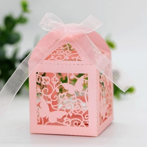 Macro detail of laser-cut pink wedding favor box with butterfly pattern and silk ribbon
