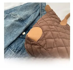 Détail du cabas en nylon matelassé marron avec renforts en cuir sur veste en jean