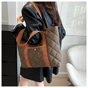 Detailed close-up of brown quilted nylon tote bag with contrasting orange straps and snap pocket