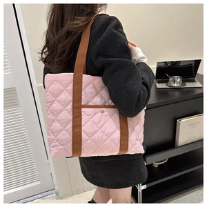 Detail of pink quilted puffer tote bag with brown straps and small front pocket