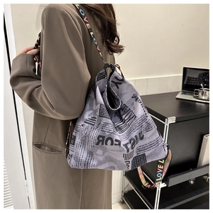 Detailansicht der grauen Oxford-Tasche mit Zeitungsdruck und LOVE-Schultergurt