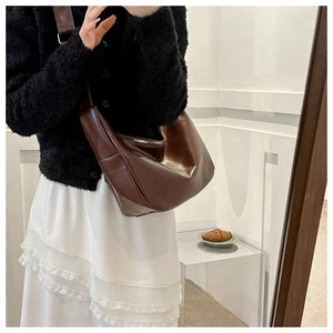 Detail of a minimalist dark brown crescent hobo bag in glossy leather with wide shoulder strap