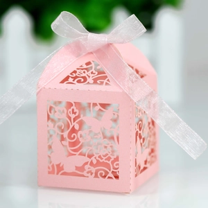 Close-up of pink laser-cut candy box with butterfly patterns and white ribbon bow