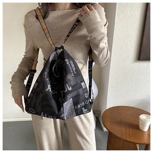Detail eines schwarzen Rucksacks mit Zeitungsdruck und bunten LOVE-Buchstabenriemen