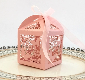 Detail of pink laser-cut wedding favor box with butterfly patterns and silk ribbon bow