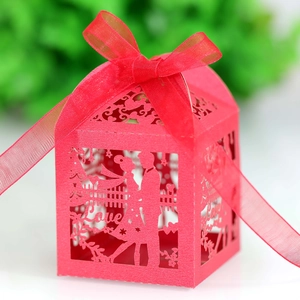 Close-up of red laser-cut wedding favor box with Love pattern and silk ribbon