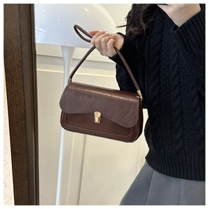 Close-up of vintage brown leather handbag featuring a textured finish and golden metal clasp