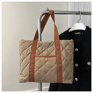 Detailed close-up of khaki quilted tote bag with diamond texture and brown straps