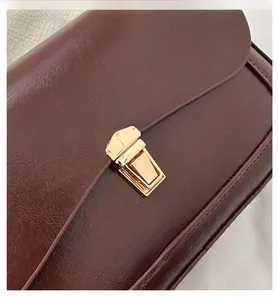 Detailed shot of dark brown leather texture and golden metal buckle on retro flap bag