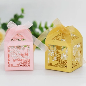 Detail of laser-cut flower and butterfly patterns on pink and gold wedding favor boxes