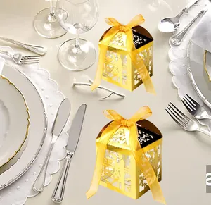 Detail of gold hollow wedding candy box with laser-cut love pattern and yellow ribbon