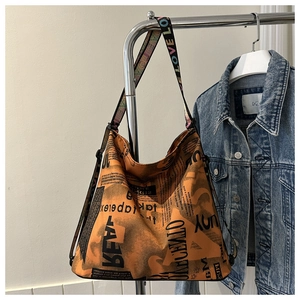 Detail der orangefarbenen Canvas-Tasche mit Zeitungsdruck und bunten LOVE-Trägern