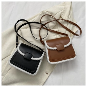 Detail of black and brown leather crossbody bags with white faux shearling trim accents