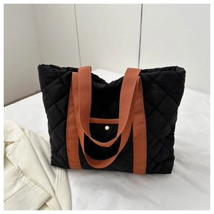 Detailed view of black quilted tote bag with brown straps and spacious interior structure