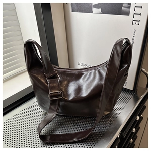 Detail of a vintage dark brown crescent bag with smooth glossy faux leather texture