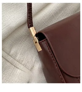 Detailed close-up of dark brown leather texture and light gold geometric metal hardware