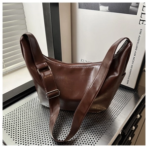 Detail of dark brown wax leather crossbody bag with adjustable strap and metal zipper